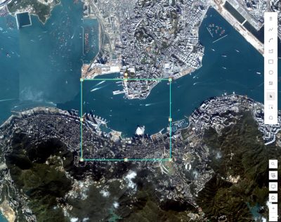Satellite image of a wildfire in a forested area near a coastline with an inset data panel showing metadata in text and icons 