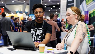Two people looking at a laptop together in a conference expo hall