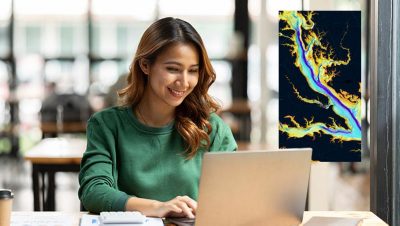 Femme souriant alors qu’elle regarde un ordinateur portable affichant une carte colorée