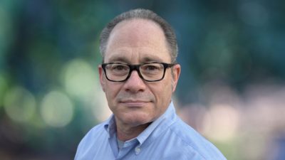Portrait d’Adam Carnow souriant, en chemise bleu clair