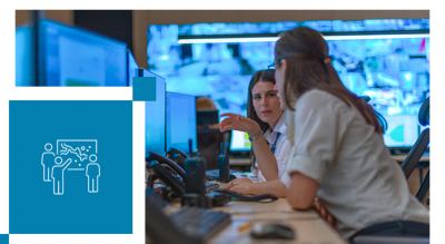 Two individuals are working together in a control room environment, surrounded by multiple monitors displaying various data and visuals.
