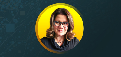 Portrait of Amber Horrie smiling in a black cowlneck shirt with a flat gray background