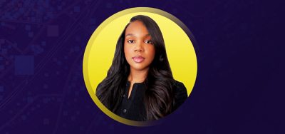 Anisha smiling in a black sweater overlaid on a yellow and purple background