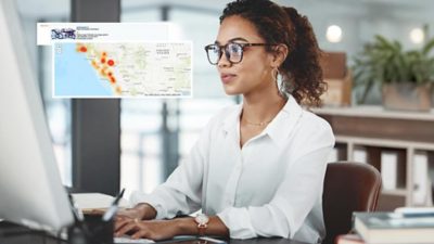 Femme avec des lunettes travaillant sur son ordinateur portable et en encart, carte avec des données de séisme