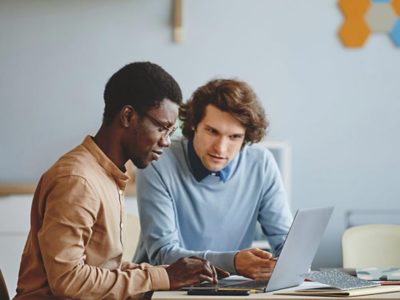 Deux collègues travaillent ensemble à une tâche partagée sur un ordinateur portable, dans un bureau moderne