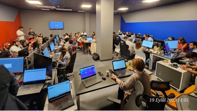 A spacious classroom with rows of computer workstations, and people sitting at them
