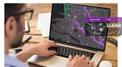 Jeune homme portant des lunettes à un bureau travaillant sur un ordinateur portable avec une petite image de données et de diagrammes à barres