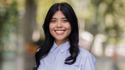 Mae smiling in a collared shirt in a modern, light-filled room
