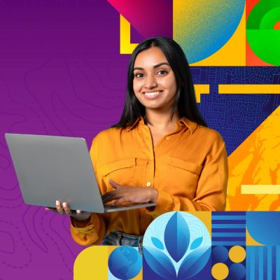 Smiling person with short dark hair wearing a black button up shirt with bold geometric designs