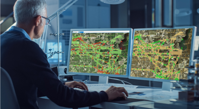 Man looking at digital maps on multiple desktop computers 