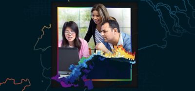 Three professionally-dressed people share a laptop in an office setting