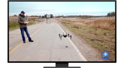A person operating a drone outside in the middle of an empty road