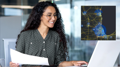 Person with long, dark, wavy hair smiles while using a laptop to browse data; a small dark map dotted with numbers is inset on the right
