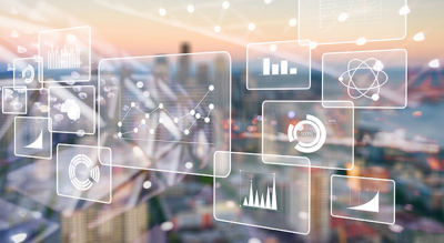 A futuristic visualization of digital analytics displayed as transparent overlays against a blurred urban cityscape.