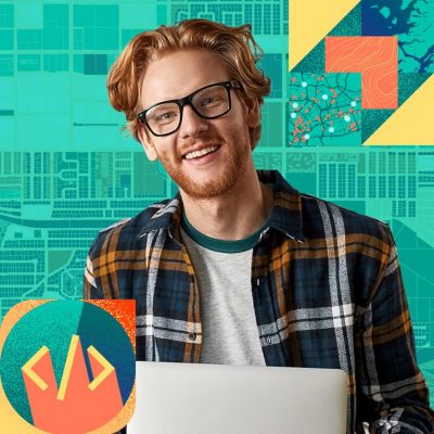 Smiling person wearing dark-framed glasses and a flannel shirt holding a laptop