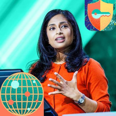 Presenter with long dark hair wearing a vibrant orange sweater gesturing emphatically on stage