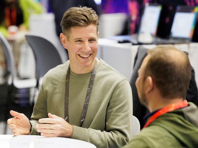 Seated event attendee smiles broadly as they interact with an Esri expert