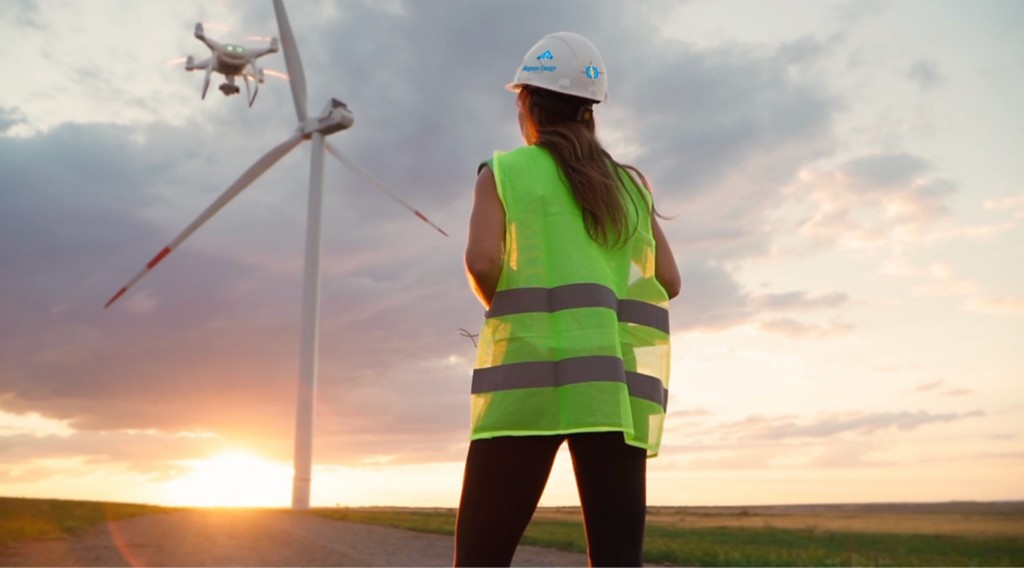 Drone pilot flies a drone in a wind farm.