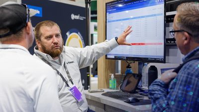 Esri staff member points to a monitor while listening to a question from a conference attendee
