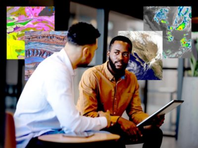 Two professionals reviewing Earth science maps, satellite imagery, and geologic data on a tablet in a modern office