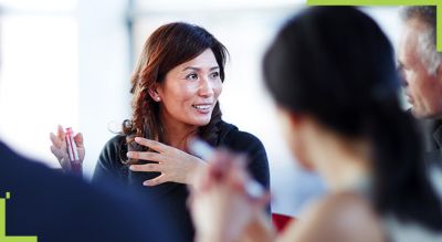 A person sitting at a table with two colleagues talking
