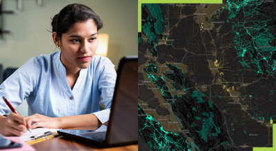 A person sitting at a desk taking notes with a pen and paper looking at a laptop, and a map 