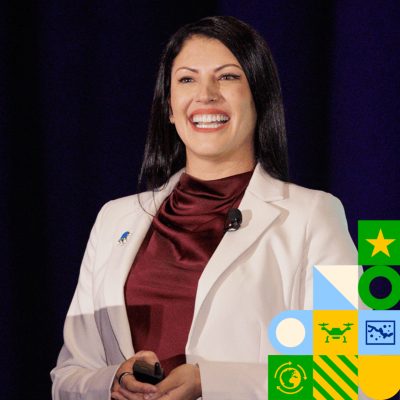 Smiling presenter wearing a cream jacket and maroon blouse overlaid with colorful tech-themed icons