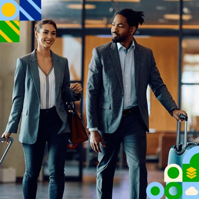 Two people dressed in business attire walking side-by-side with rolling suitcases