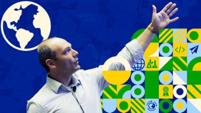 Presenter gesturing upward against a blue background overlaid with a globe graphic and tech-themed icons