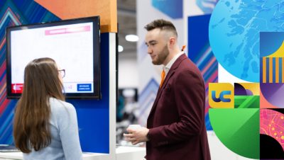 Man with burgundy suit talking to an attendee 