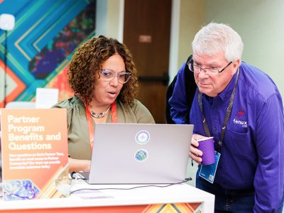 Esri expert showing their laptop screen to an attendee wearing a purple fenux labs dress shirt