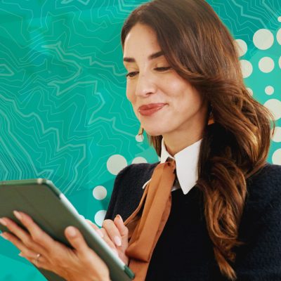 A professional woman looks down and smiles while using a digital tablet