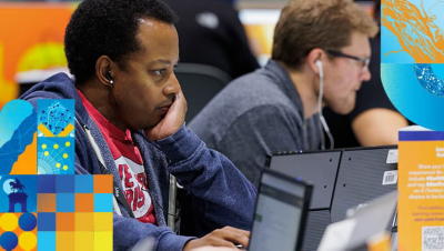 Attendees wearing earbuds working intently on laptops at the event