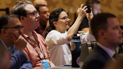 A member of the audience at a presentation raises a hand to ask a question
