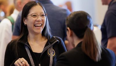 Two people in conversation at a conference networking event - one is laughing
