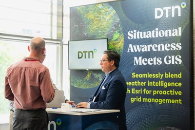 Three people speaking in front of the DTN exhibit at the Esri UK Annual Conference 2025