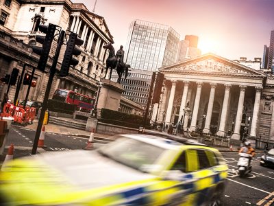 blurry image of police car going past London's Royal Exchange