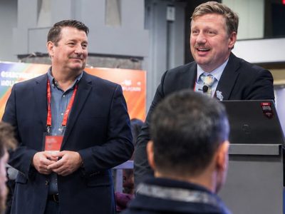 Two Esri experts with red lanyards wearing business attire giving a presentation