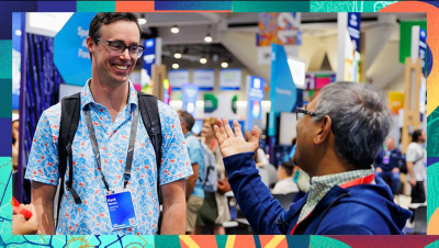 Attendees standing and talking on a busy expo floor with booths and signage in the background