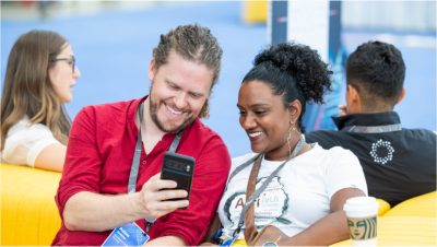 Event attendees grinning as they look at one of their mobile devices