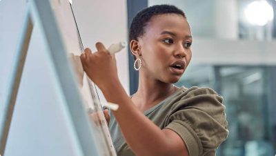  A woman is seen writing on a whiteboard in a modern office setting.