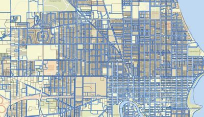 Circular view up through many multistory buildings with small balconies surrounding a patch of blue sky with clouds