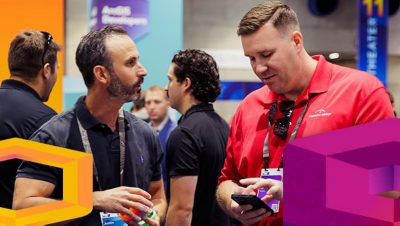 Two people conferring at an Esri expo; one is searching for something on a cell phone to show the other