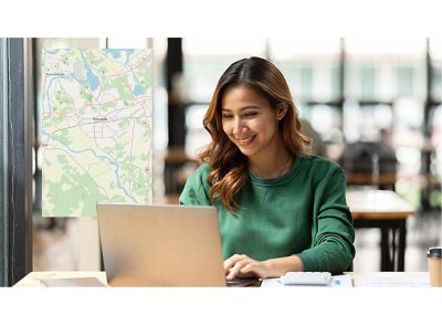 Kuvituskuva, missä nainen on läppärillä tarkastelemassa karttaa sähköverkkoon liittymistä varten