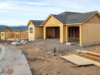 Partially built single‑story home with exposed framing and plywood walls at a residential construction site