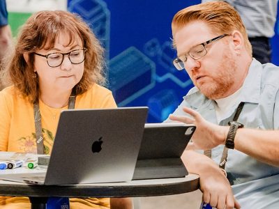 An Esri expert using a tablet to demonstrate a concept to a conference attendee