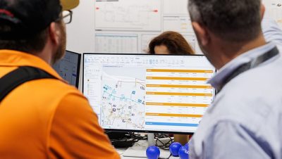 Two people looking at a computer display showing a map and a chart