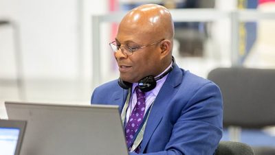 Conference attendee in a suit and tie working at a laptop in the Hands-On Learning Lab