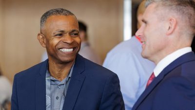 Two people interacting at a conference networking event; one smiles broadly