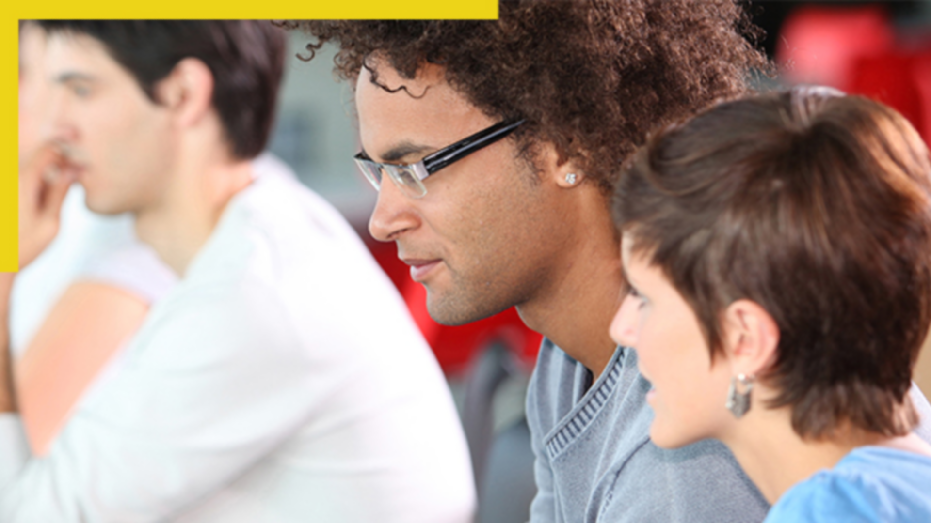 Photo of three casually dressed attendees in a group seminar setting gazing to the left at an unseen speaker or screen